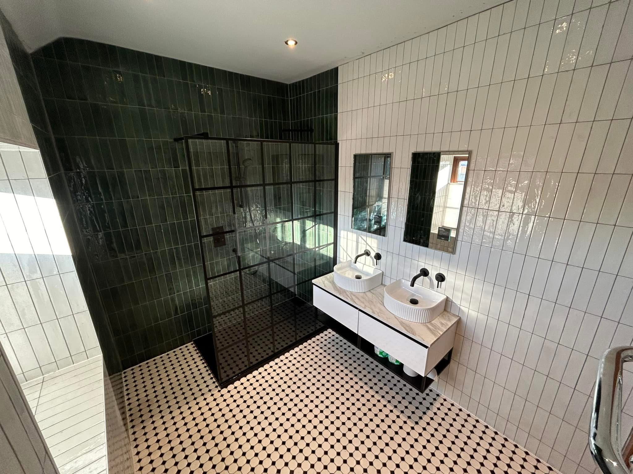 Green and white tiled bathroom with double sinks